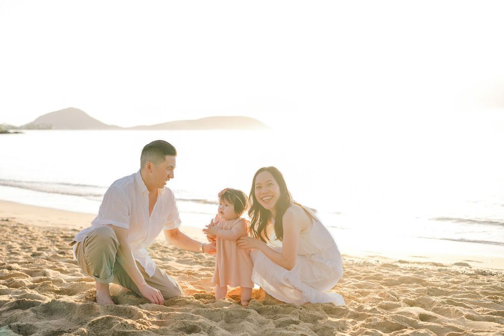 A family enjoys quality time together playing in the sand at sunset on a peaceful beach.