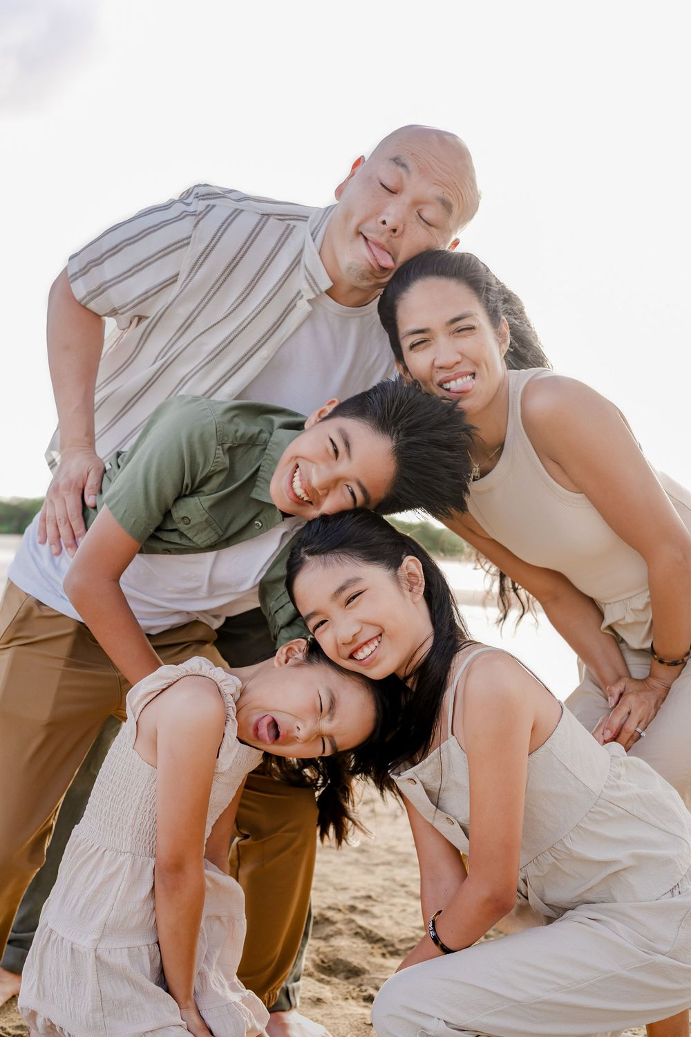 A playful group poses together on a beach in casual outfits creating a fun and candid photo series.