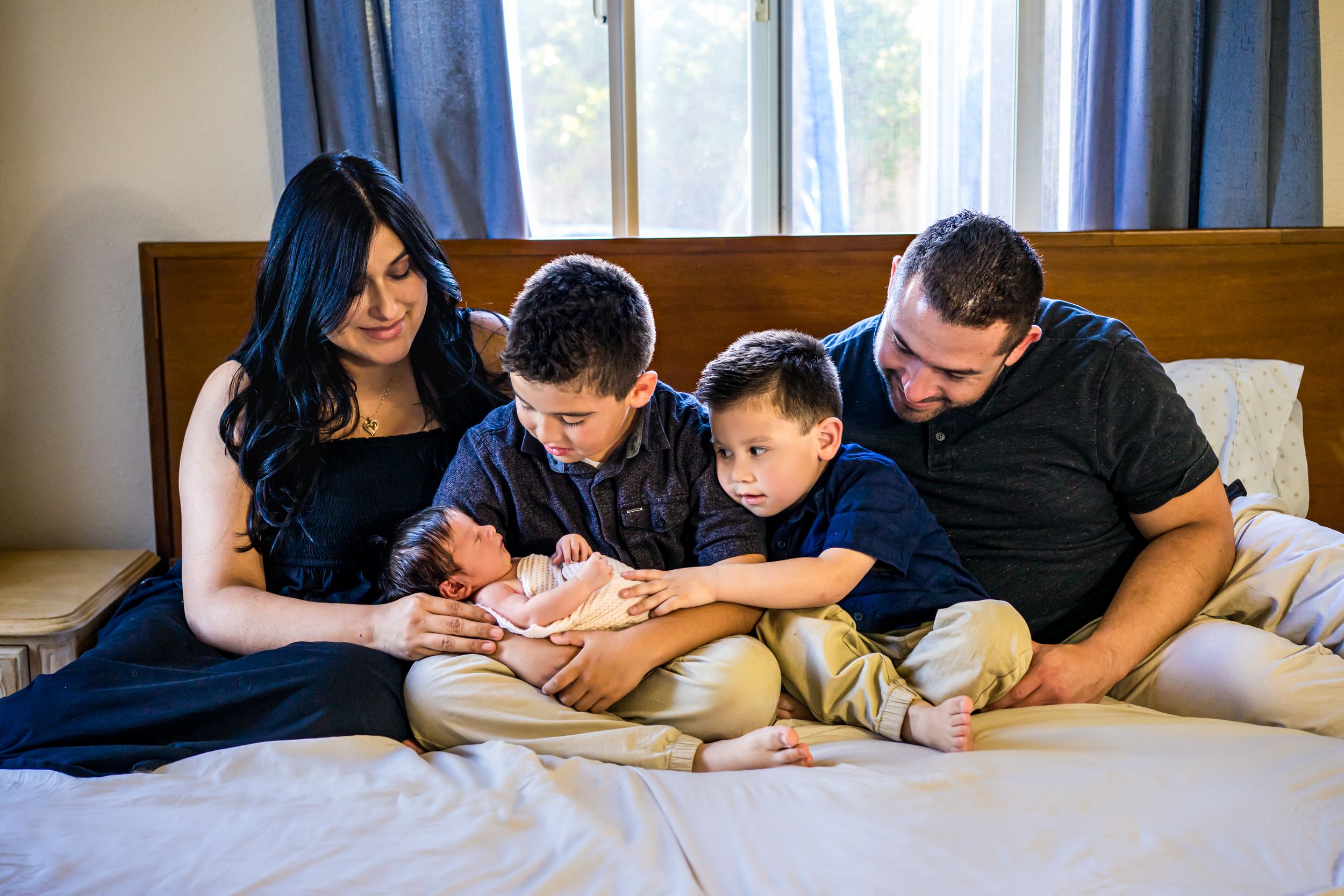 Family members relaxing together on bed in casual attire.