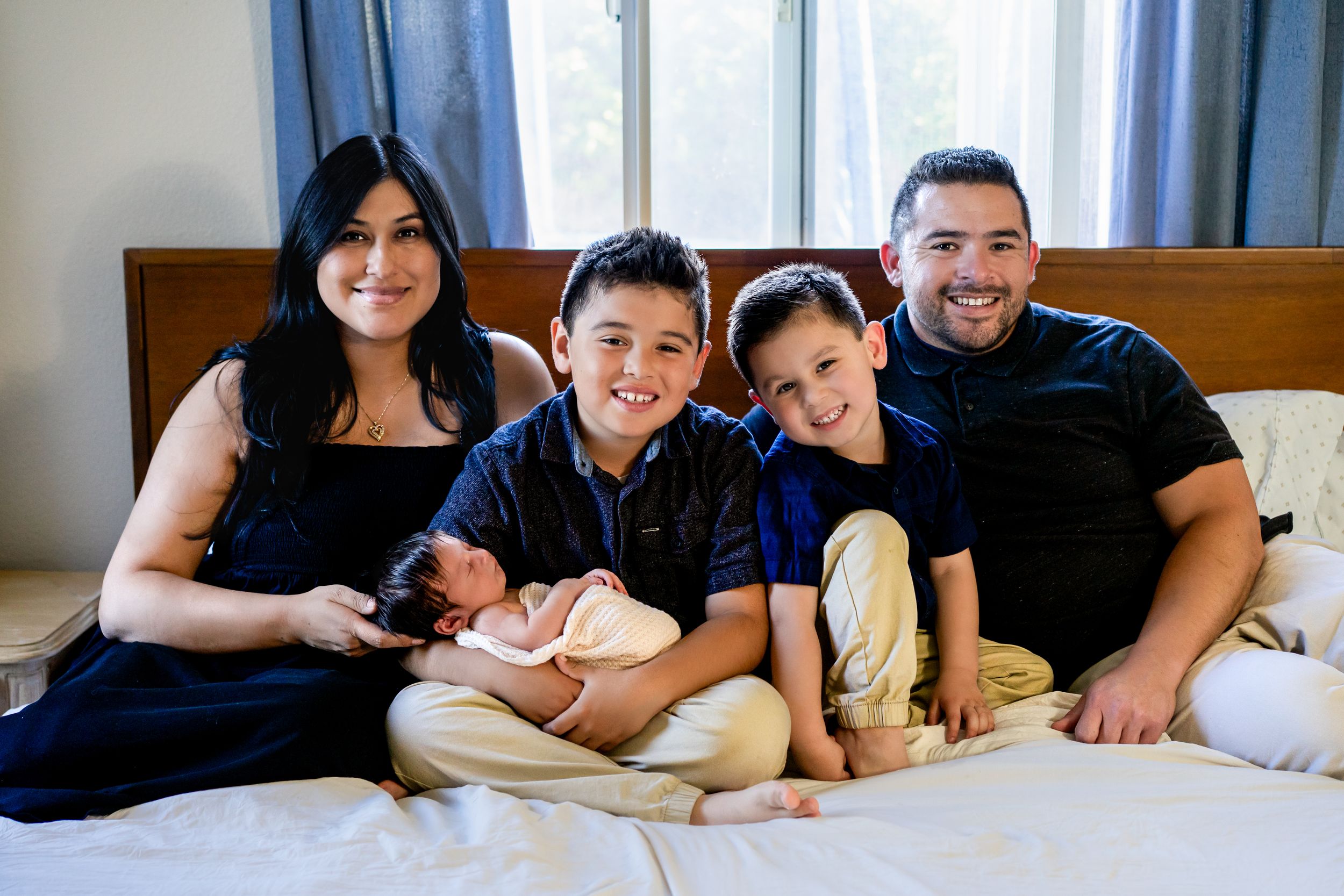 Casual family photo session with everyone lounging on bed together.