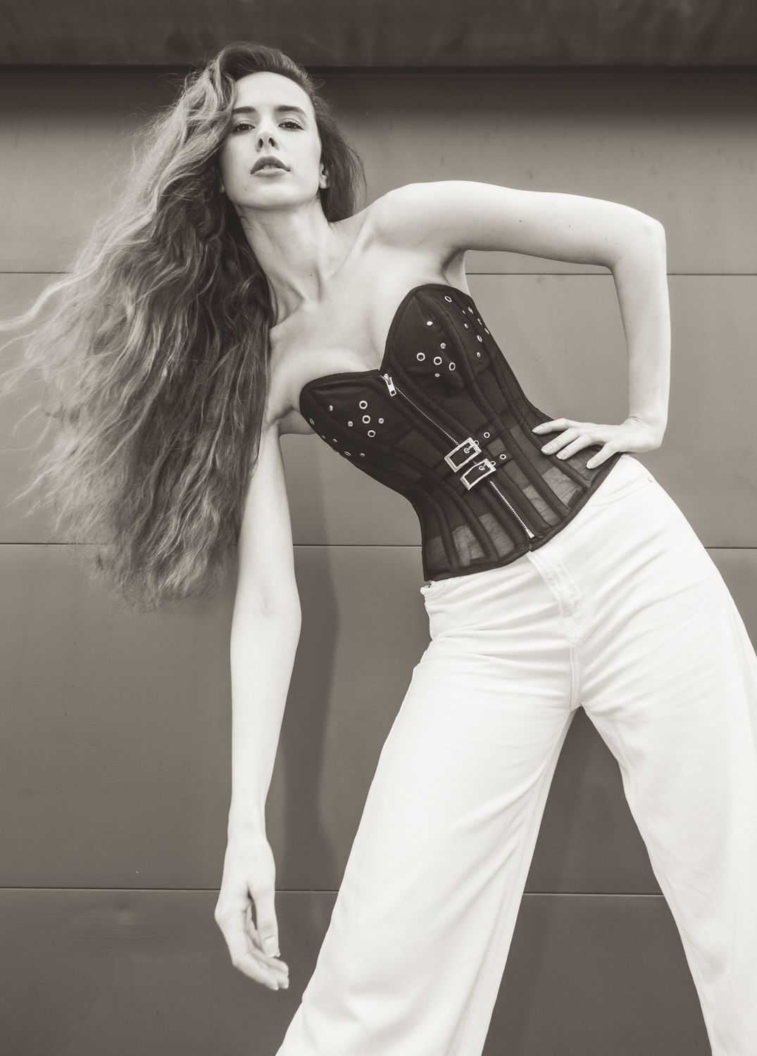 High-fashion Black and White image, long haired woman, corset top, white pants, beautiful movement and wind blowing