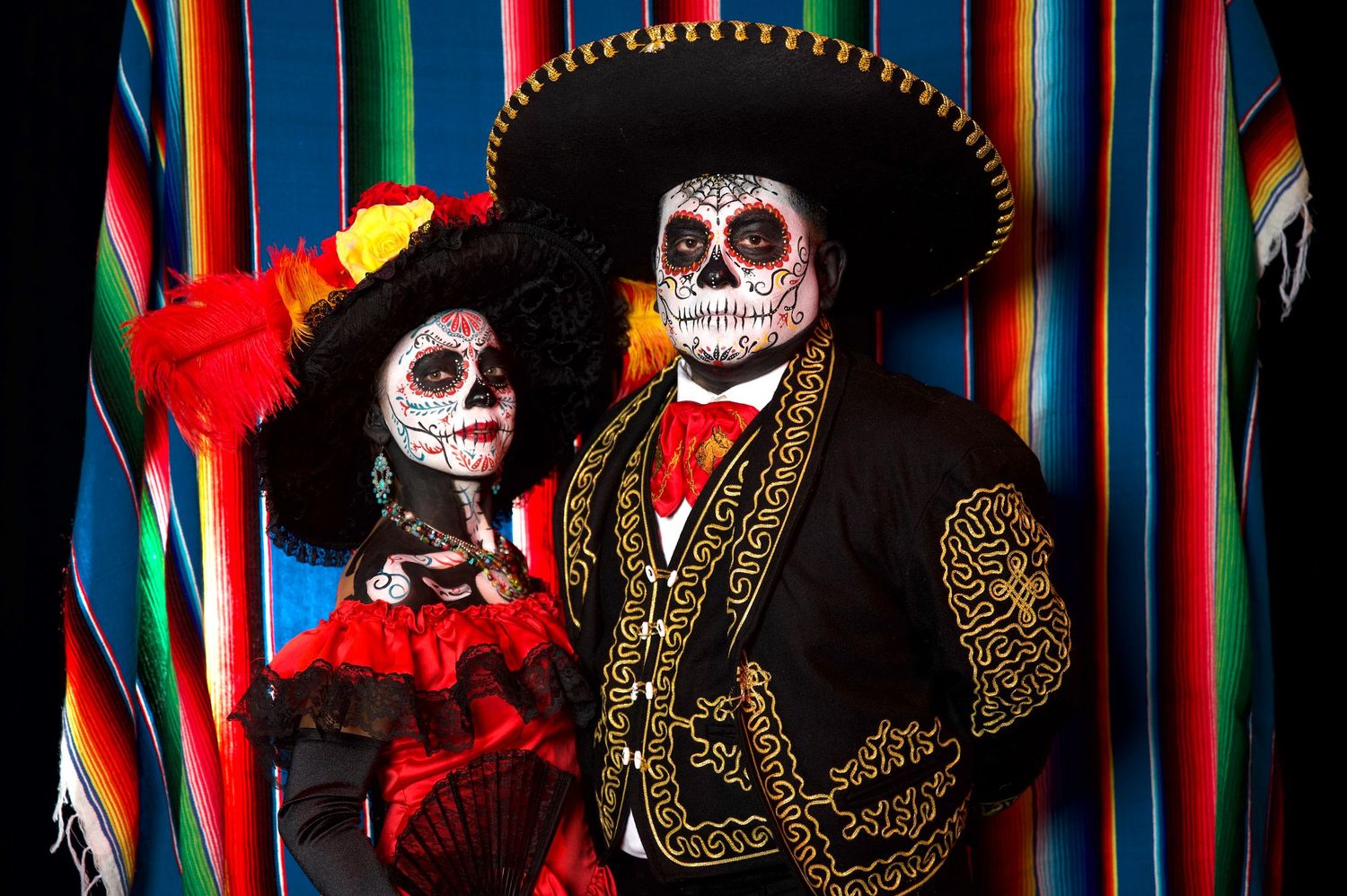 Day of the Dead themed celebration with traditional face paint against colorful striped backdrop.