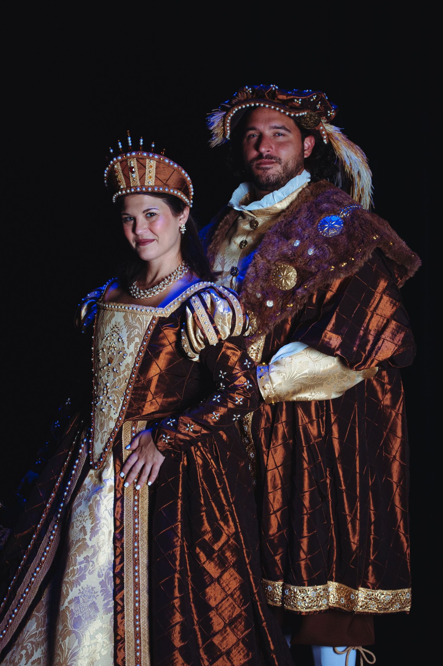 Medieval-style theatrical performers in ornate period costumes against dark background.