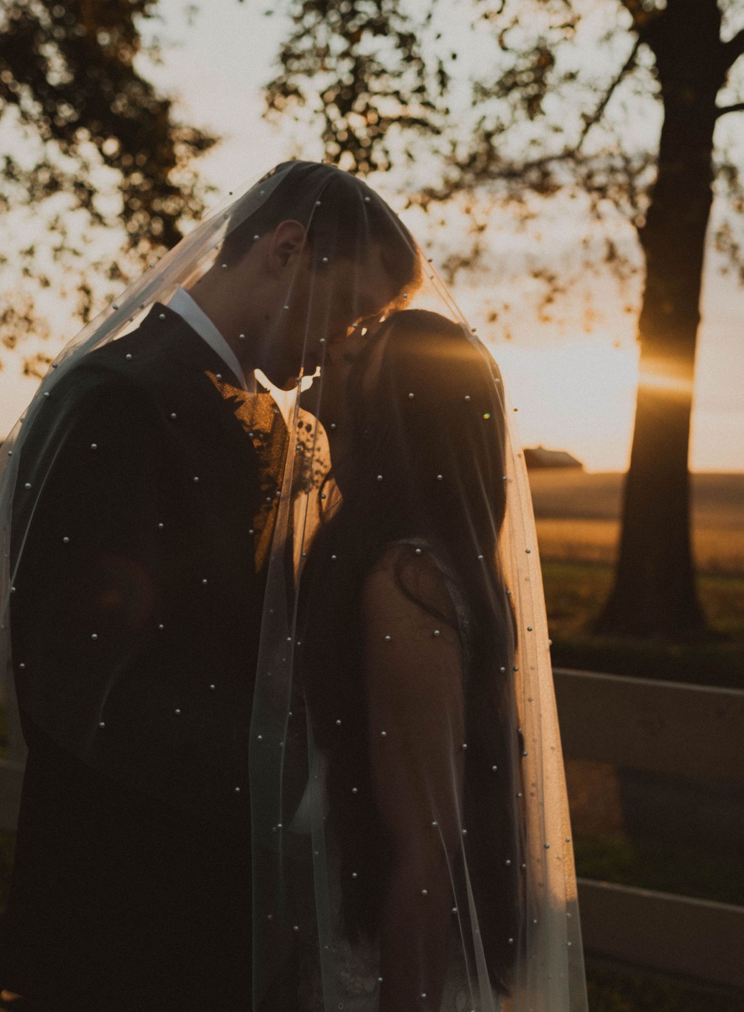 People walking up grassy hill path during sunset in rustic outdoor setting.