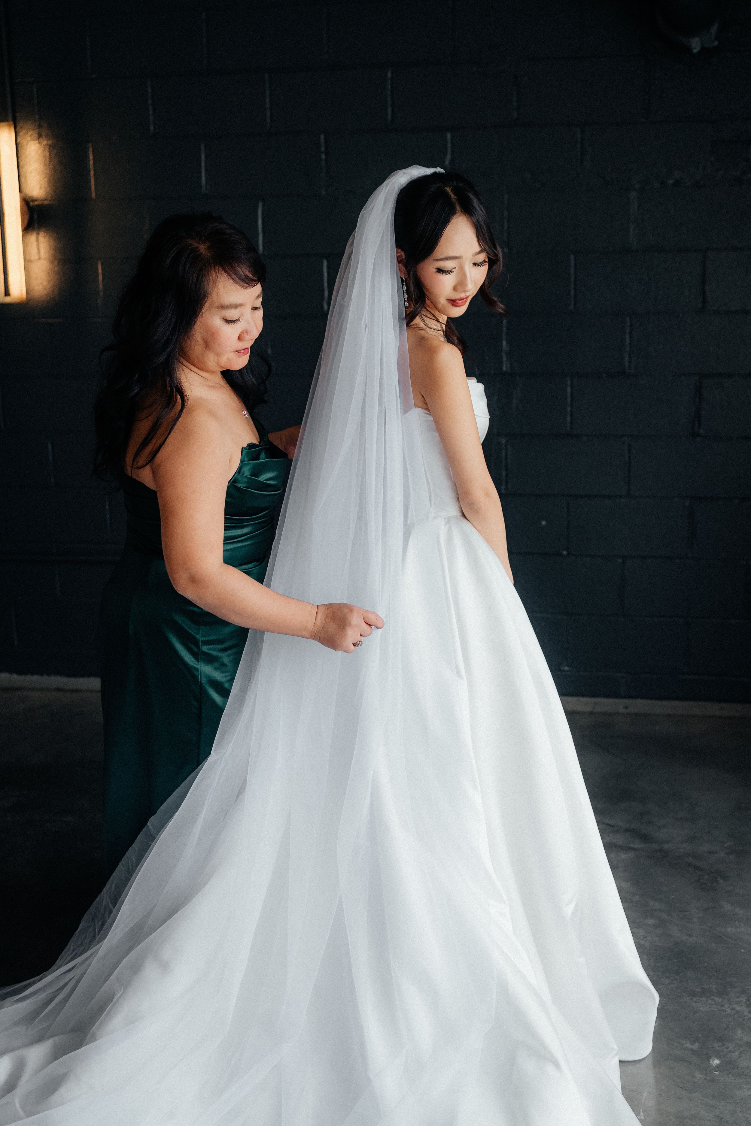Two flowing white wedding dresses captured in an artistic sequence of movement against a dark background.