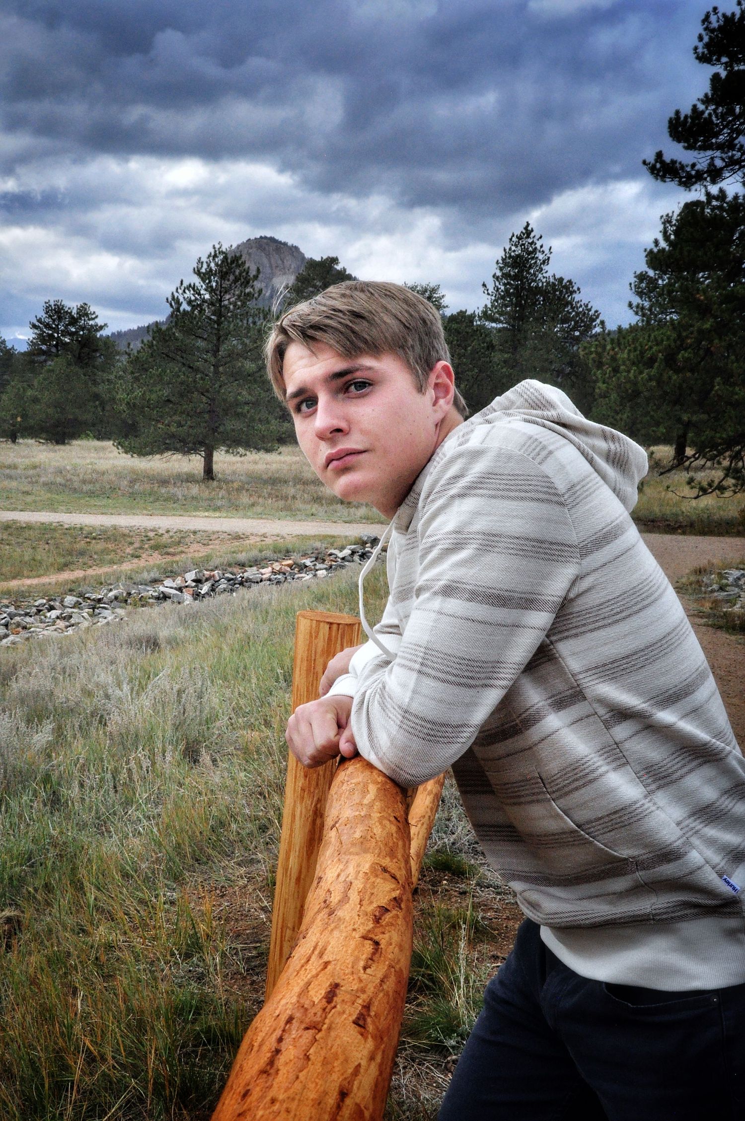 young man leaning on a fence post