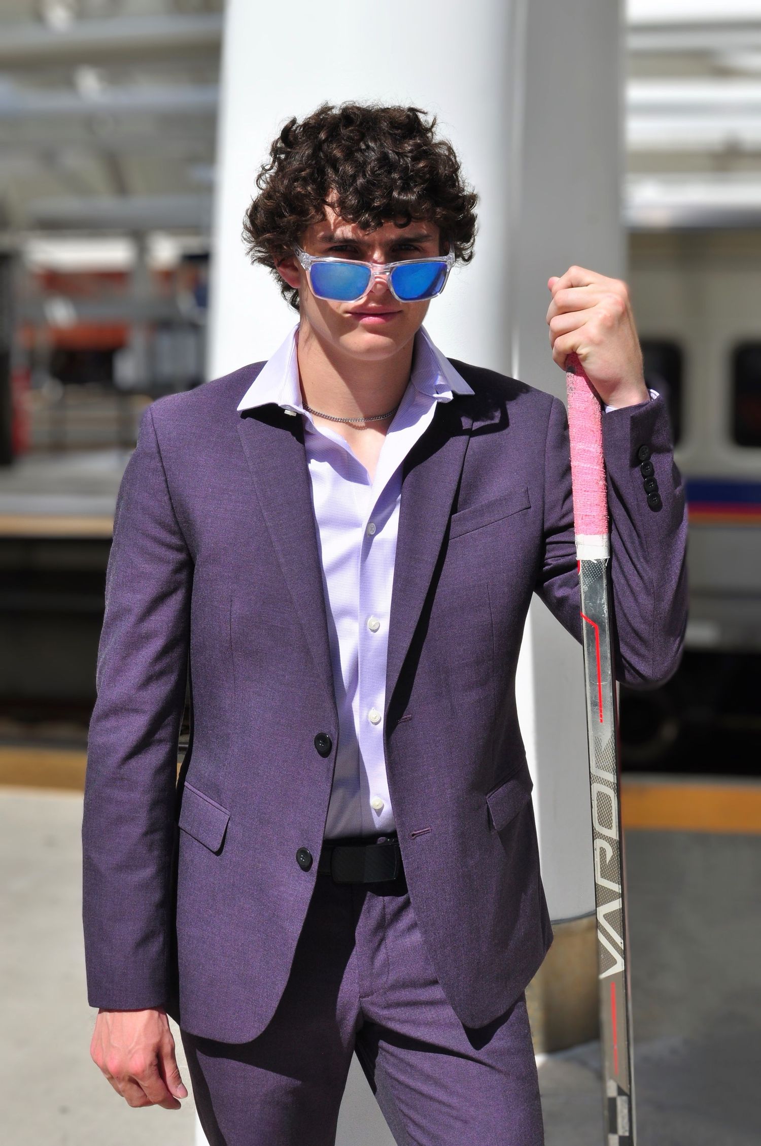 Young man in sunglasses poses with his hockey stick