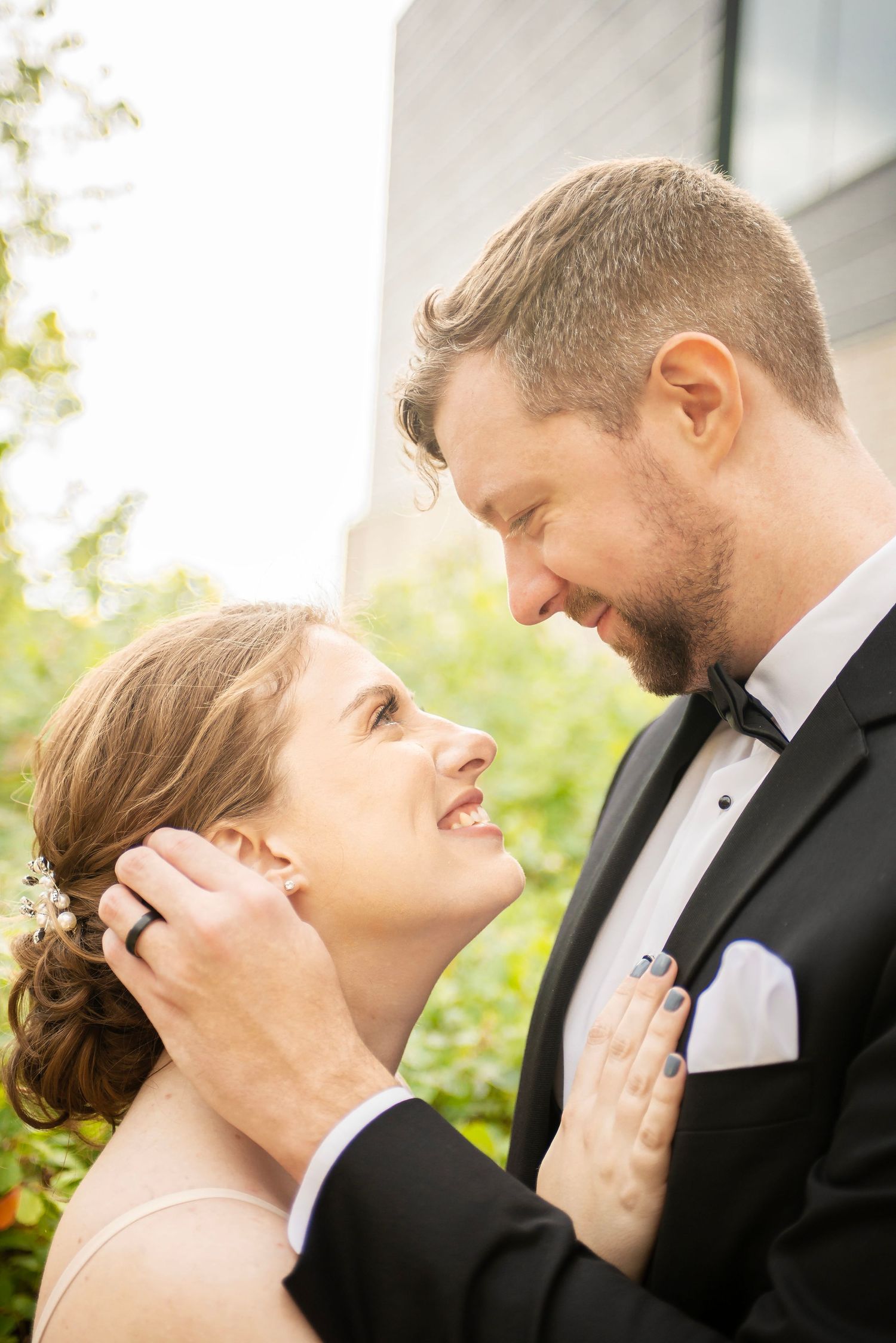 sweet authentic candid closeup wedding photo, portrait of bride and groom facing each other groom brushing hair behind her ear both smiling