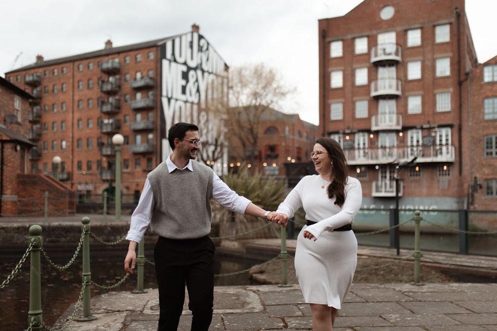 Intimate couple sharing joyful moment against rustic stone wall. Pre-wedding photoshoot.
