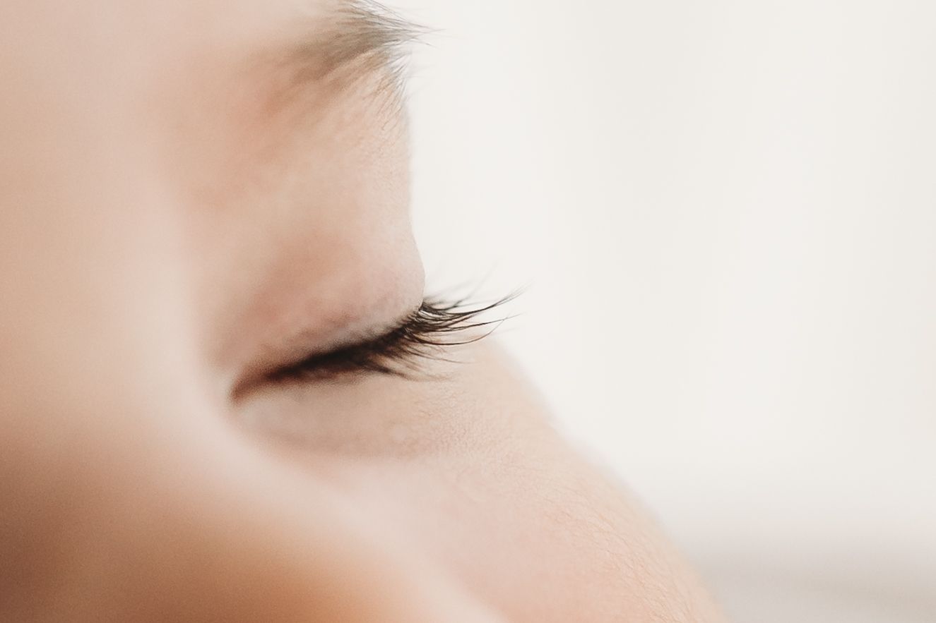 Extreme close-up macro shot of a sleeping newborn baby's delicate eyelashes and eye.
