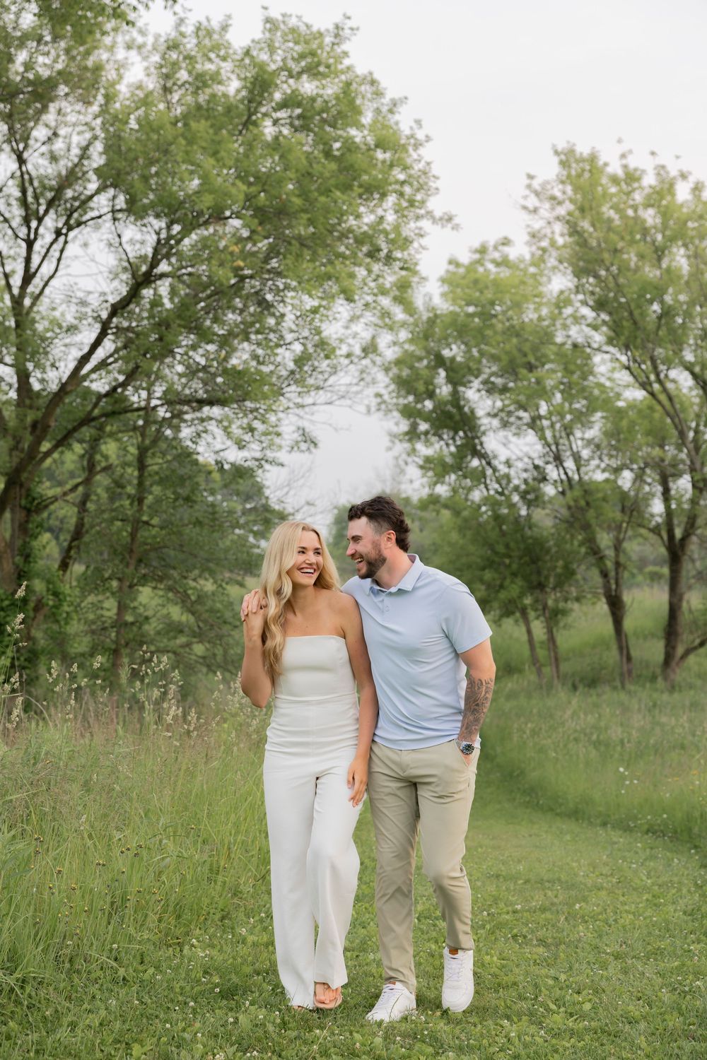 A couple walking together on a grassy path at bear creek nature park in Rochester Hills surrounded by green trees on a summer day.