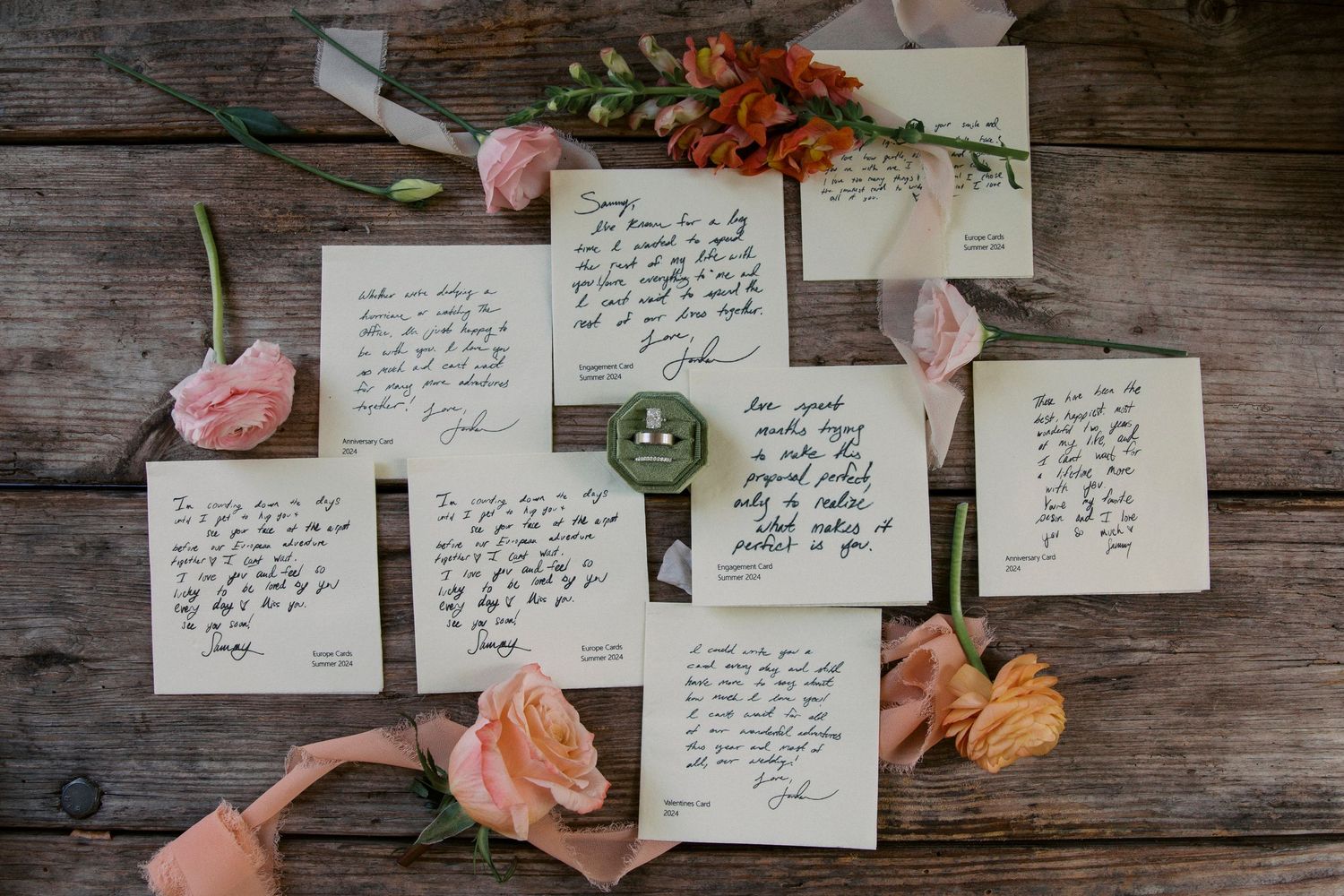 Handwritten love letters with pink roses and orange flowers on rustic wood. Wedding details at Little River Farms in Milton, Georgia.