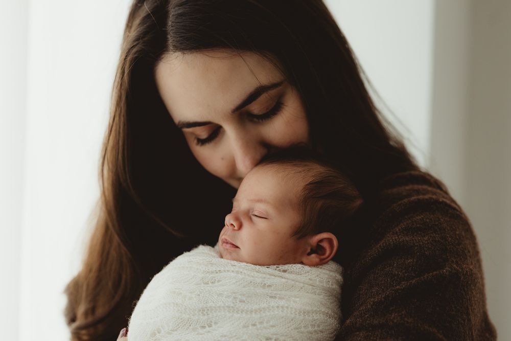 A tender moment between mother and baby as they share an intimate embrace in soft, natural lighting.