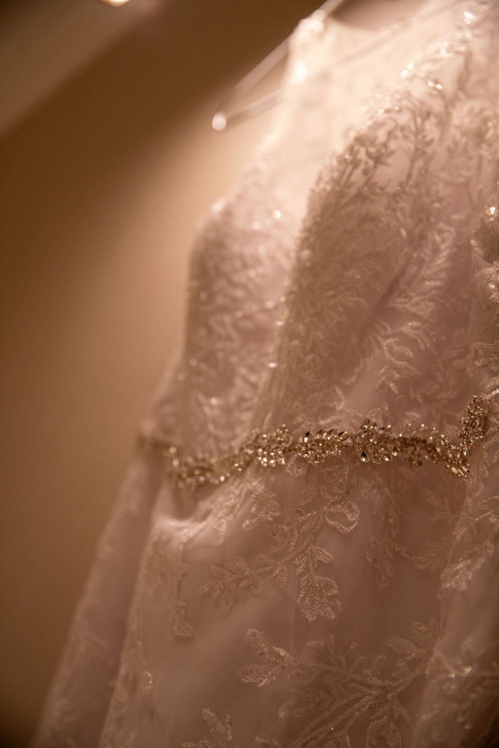 Close-up detail of intricate lace and beading on wedding dress.