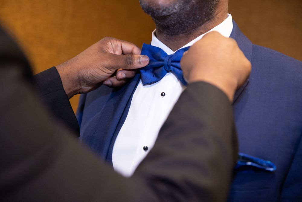 Adjusting a royal blue bowtie on formal attire.