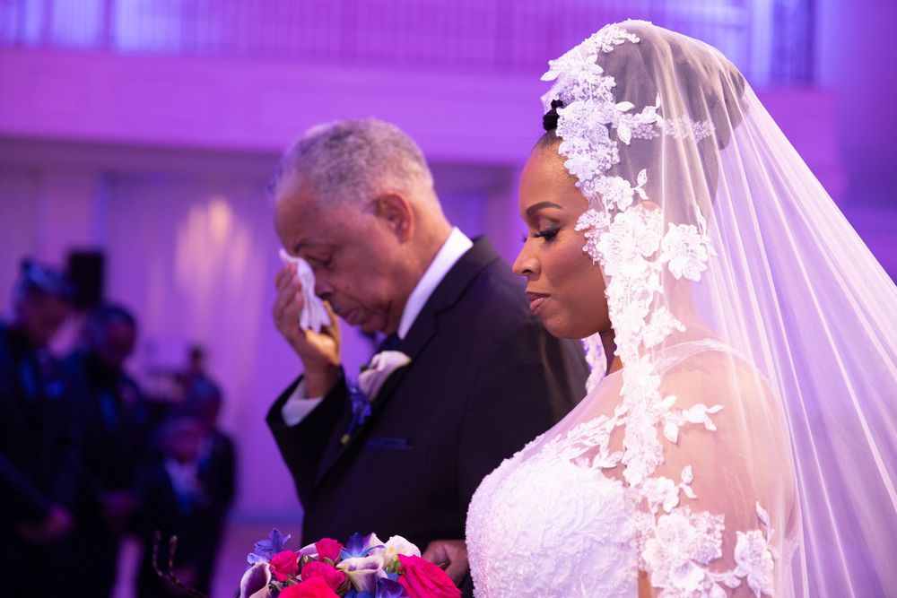 Wedding ceremony with purple ambient lighting and elegant white decor.
