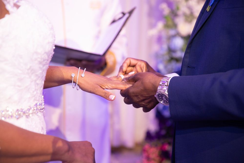 Close-up of wedding rings and hands during ceremony exchange.