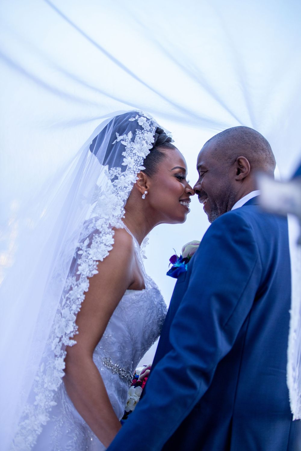 Romantic moment between newlyweds under soft lighting with white veil details.