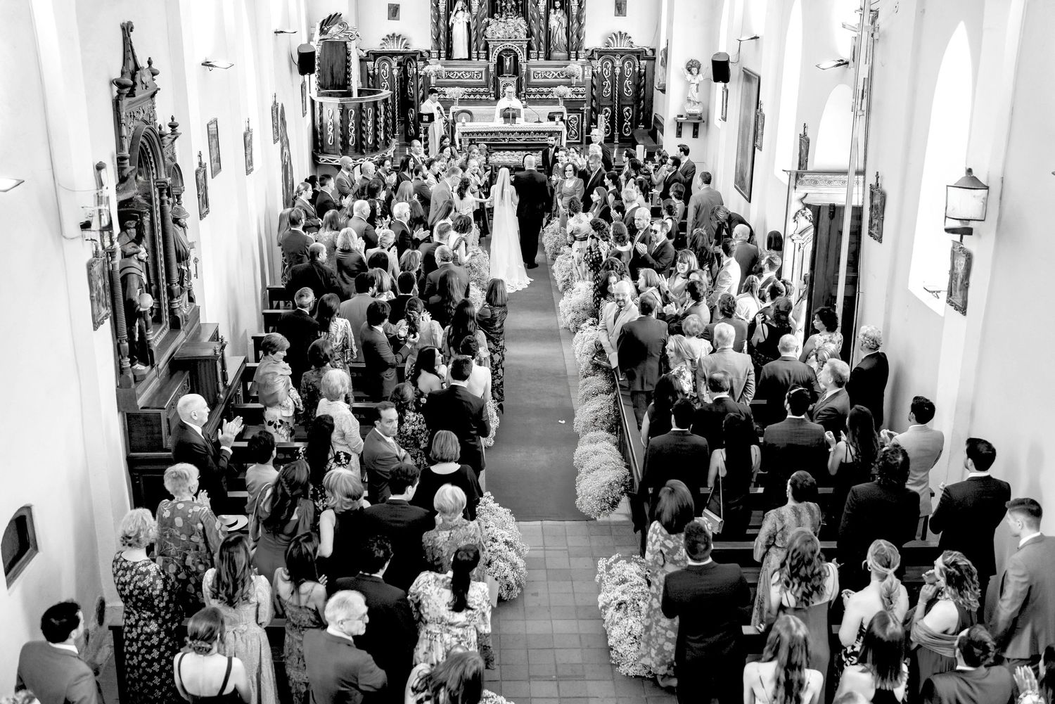 Wide angle black and white view of a crowded church interior during a ceremony.