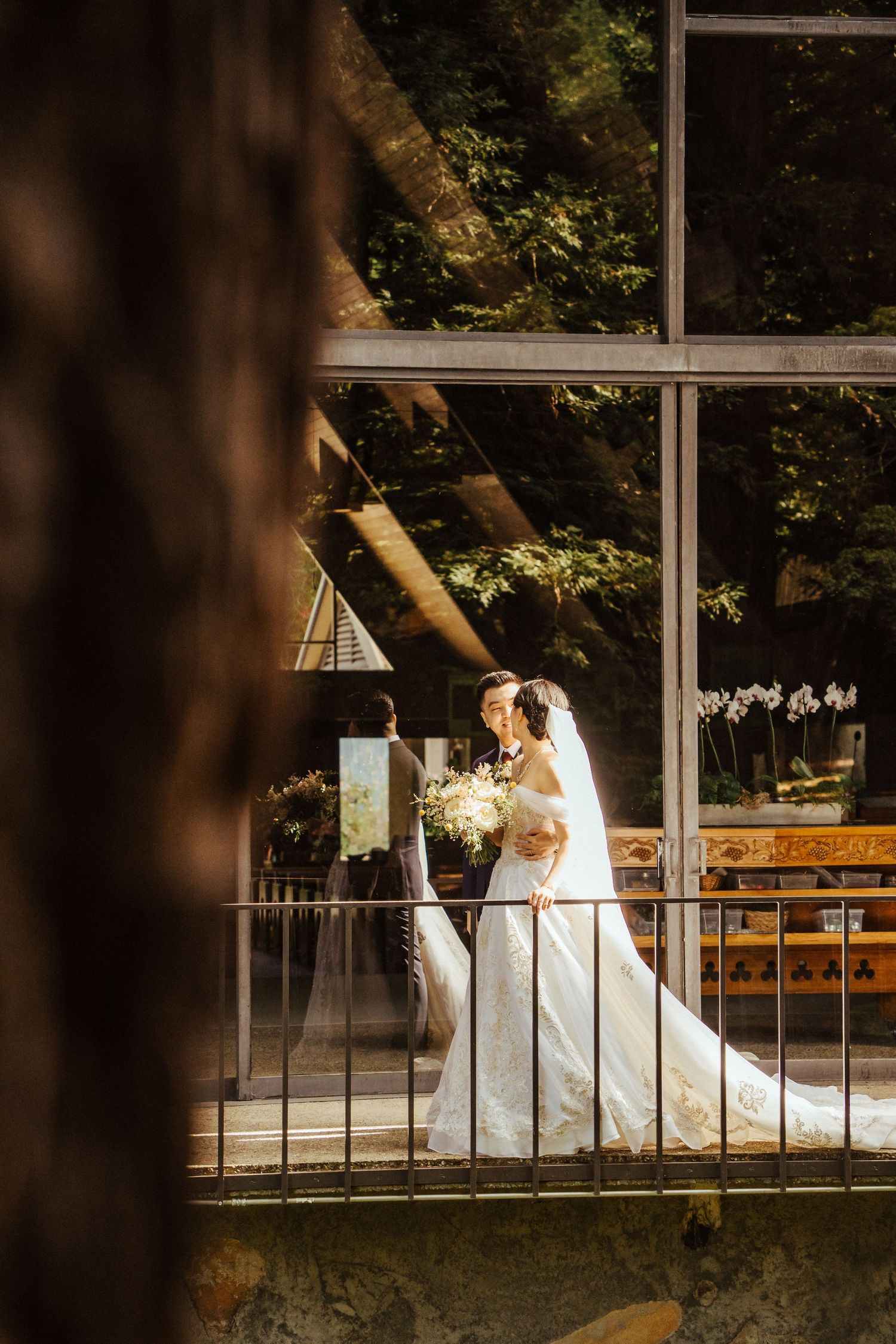 A couple in wedding attire shares an intimate moment outdoors with their two dogs.