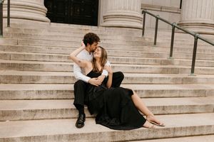 Couple sitting intimately together on grand stone staircase during engagement photo session.