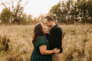 Couple shares a tender almost-kiss embrace in a golden meadow during a romantic fall engagement session.