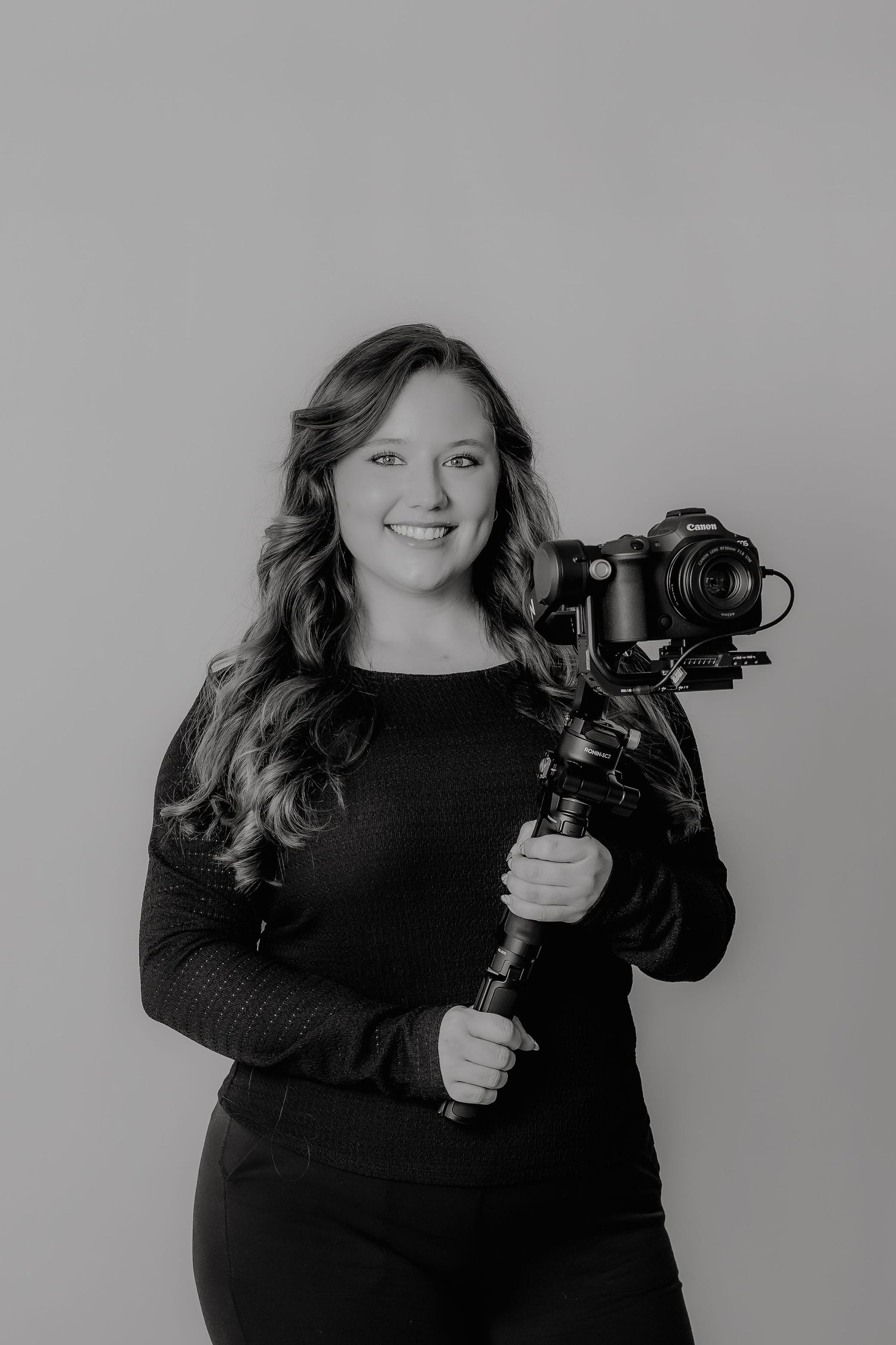 Photographer holding professional camera rig with stabilizer in studio portrait.