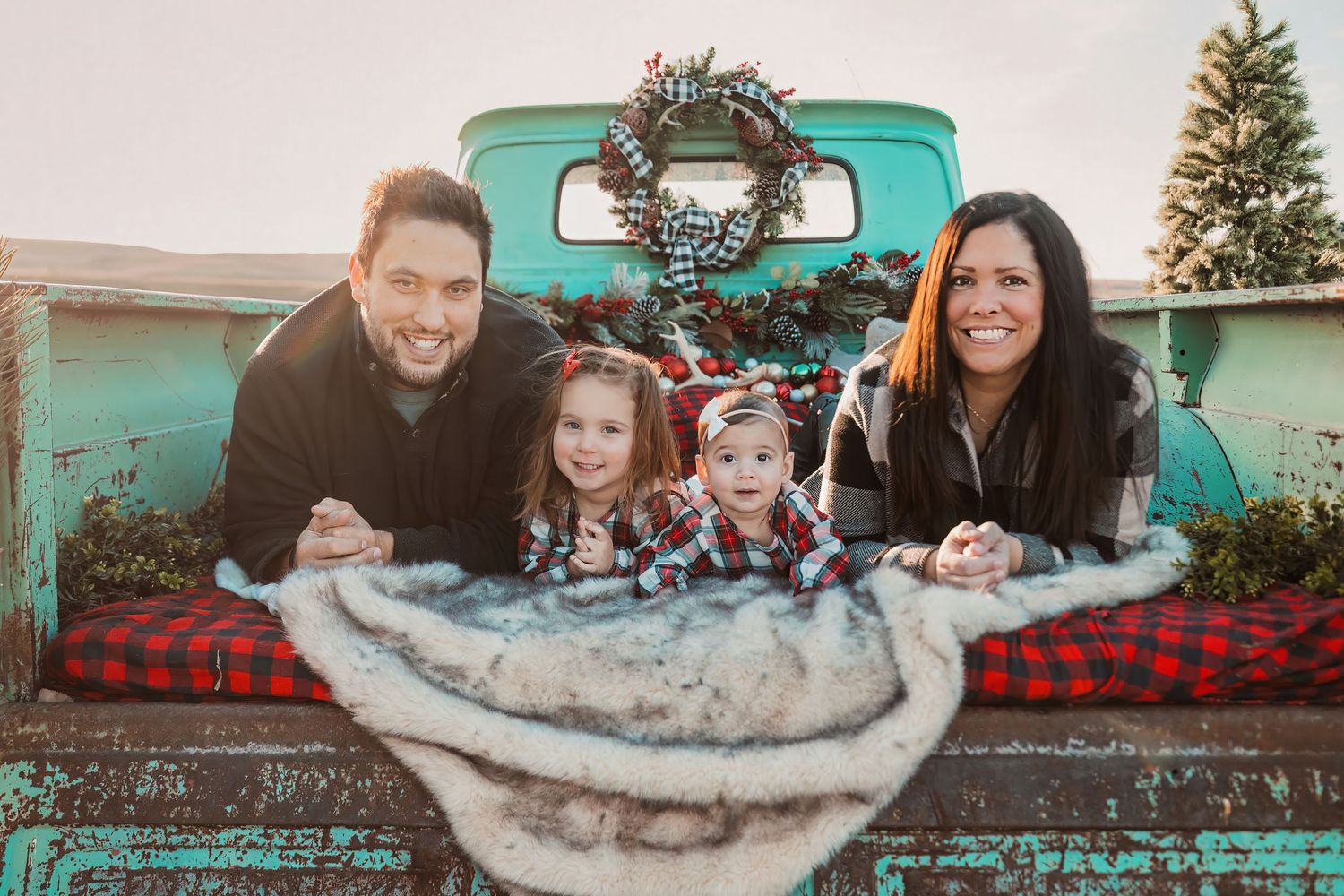 Holiday portrait with a vintage turquoise truck and buffalo plaid blanket.