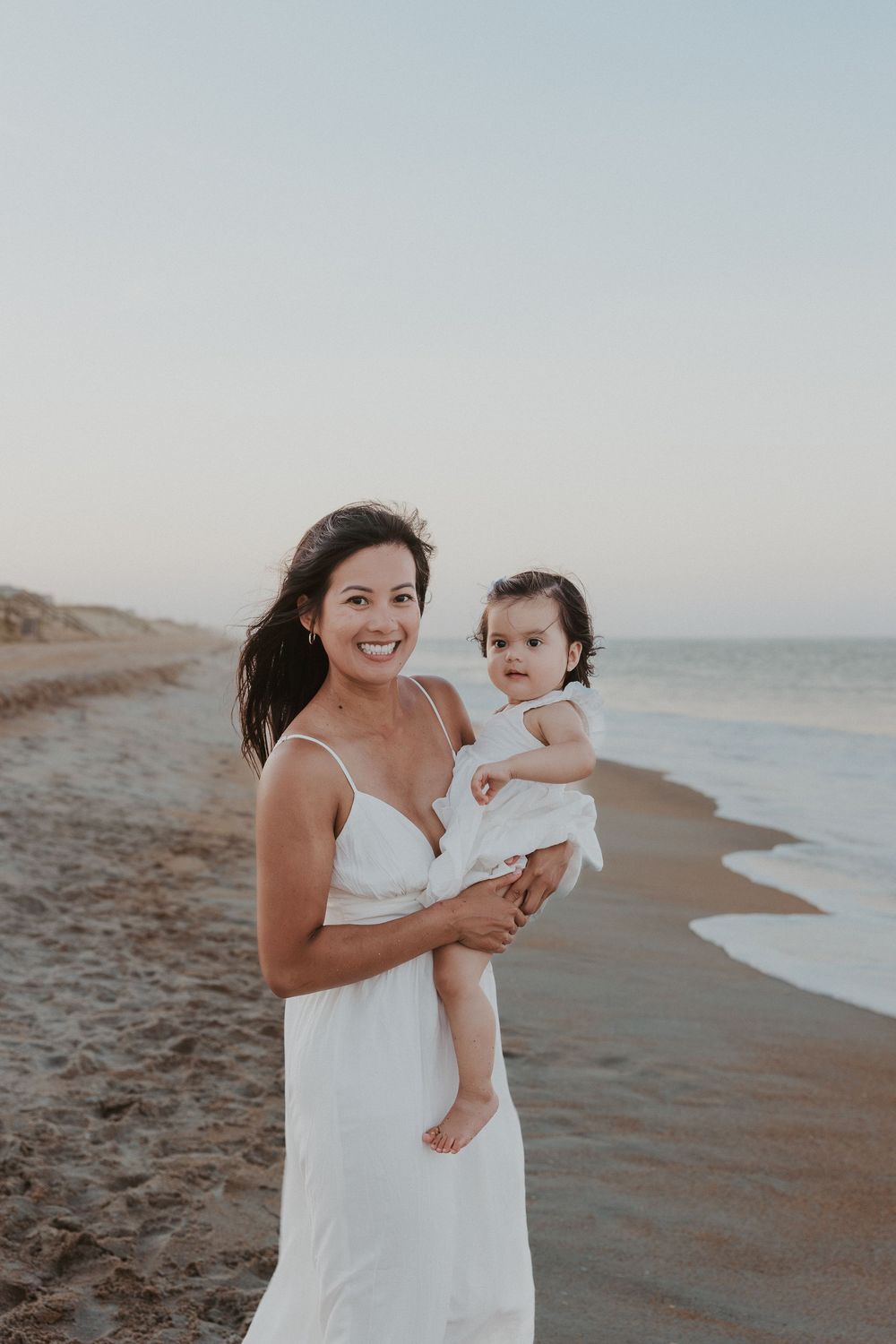 A tender moment between parent and child playing together on a sandy beach at sunset.