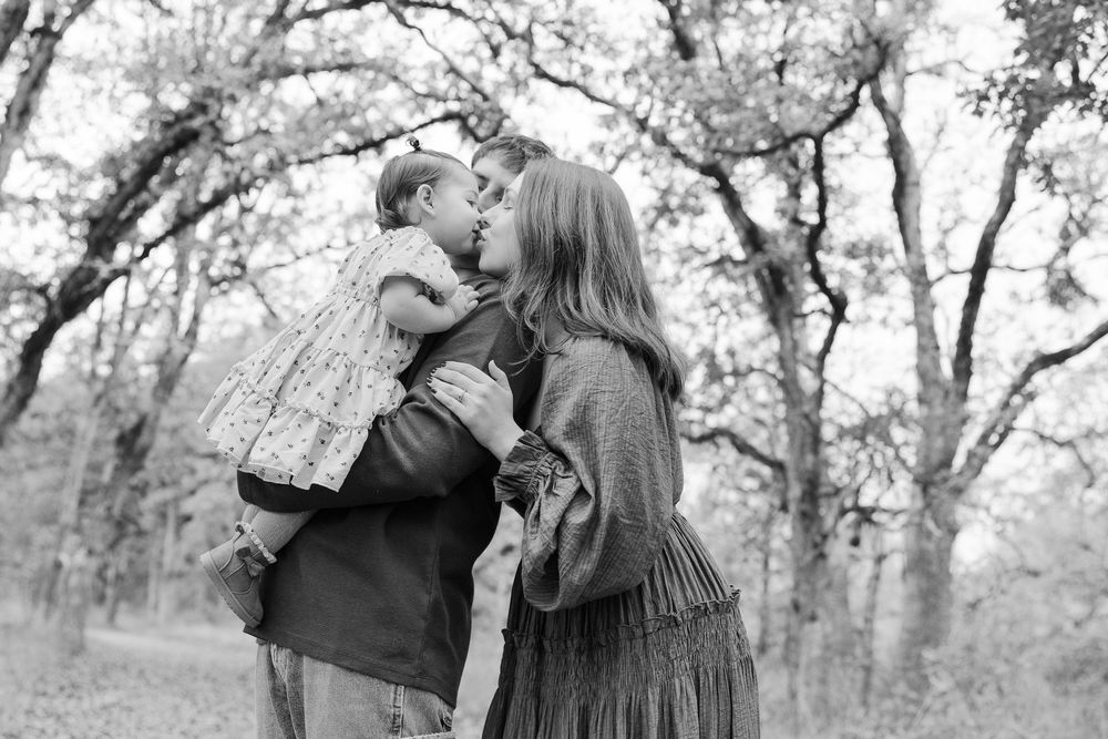 A couple embraces in a romantic outdoor photo session among autumn trees and fallen leaves.