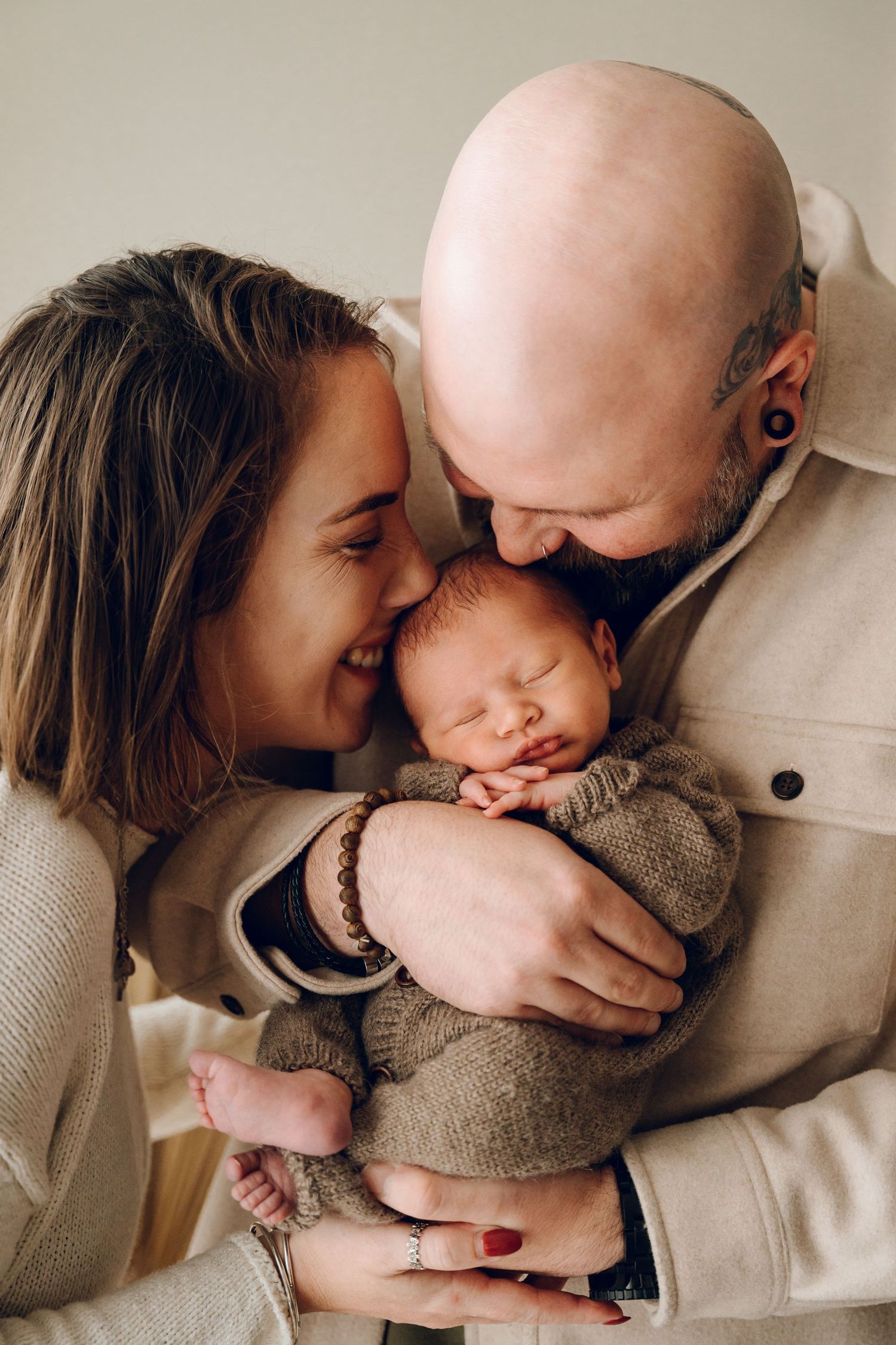 Intimate family moment with newborn baby swaddled in knit blanket.