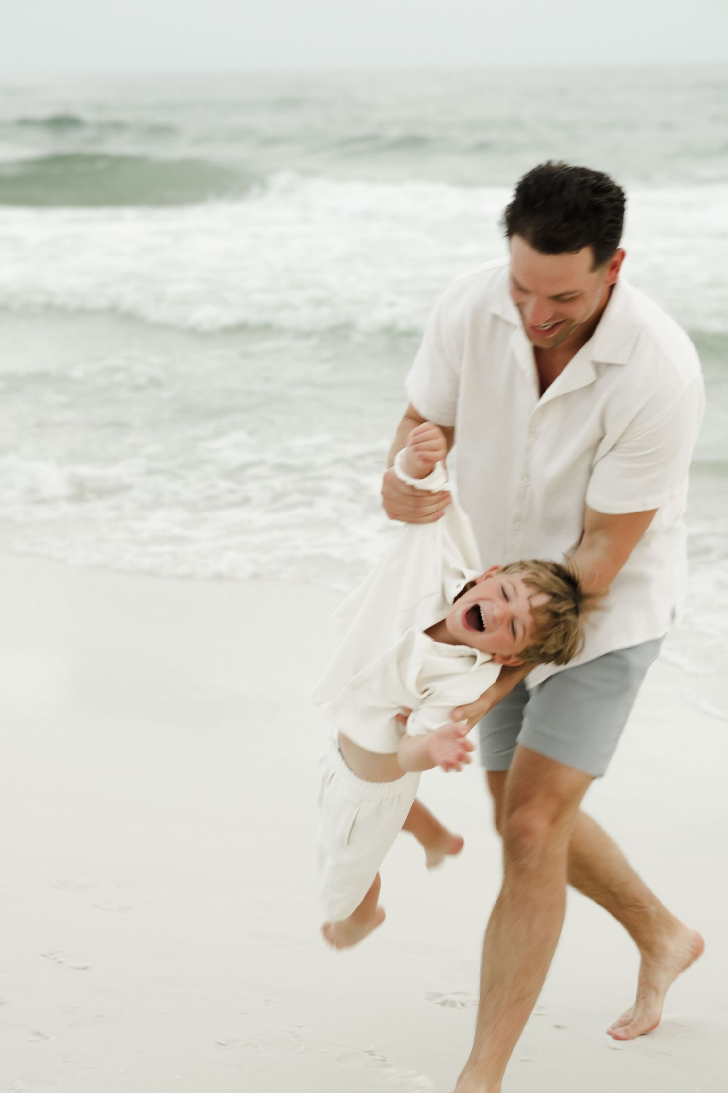 Child walking on beach wearing a patterned jumpsuit and white beanie.