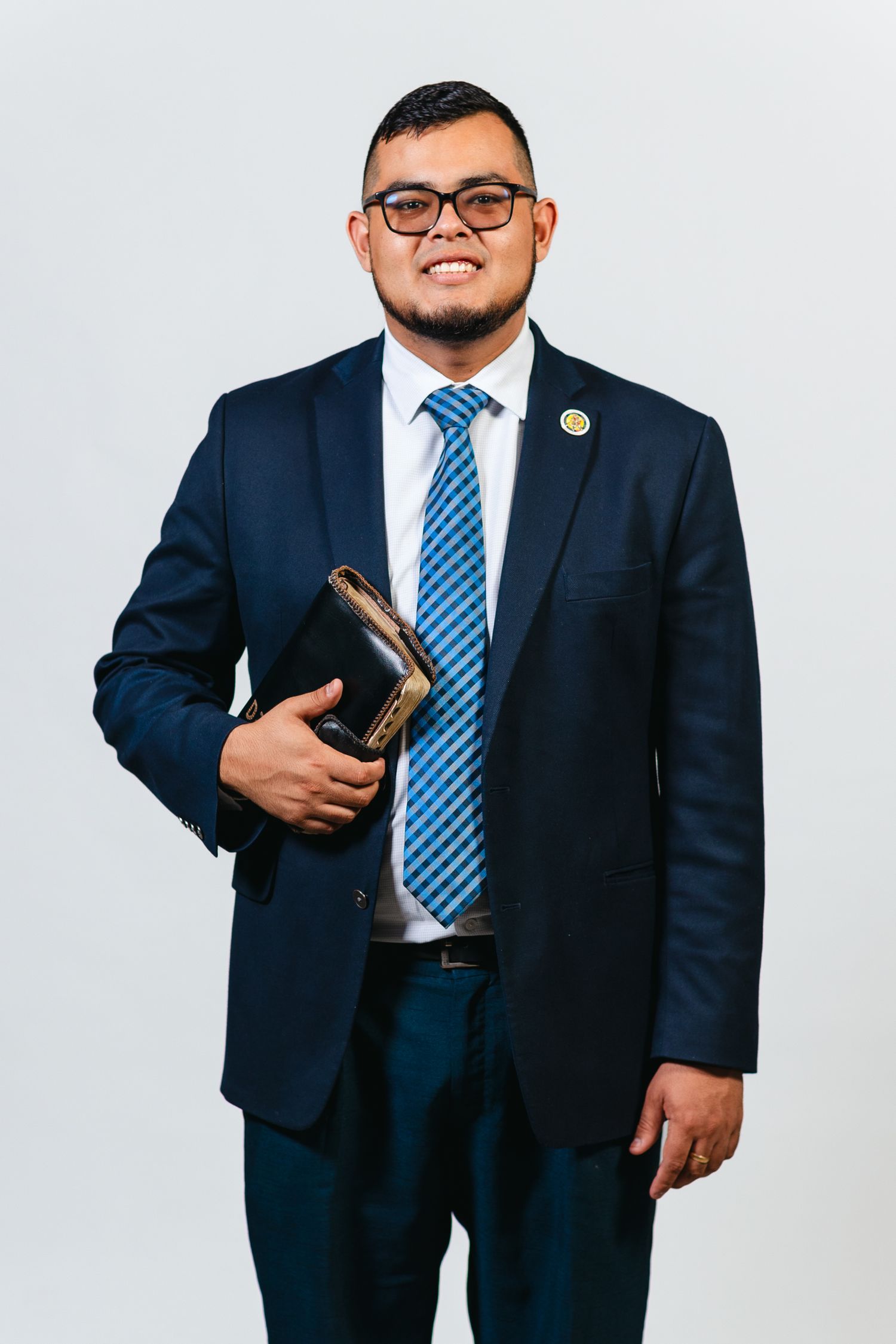 Professional in navy suit and blue striped tie holds book against white background.