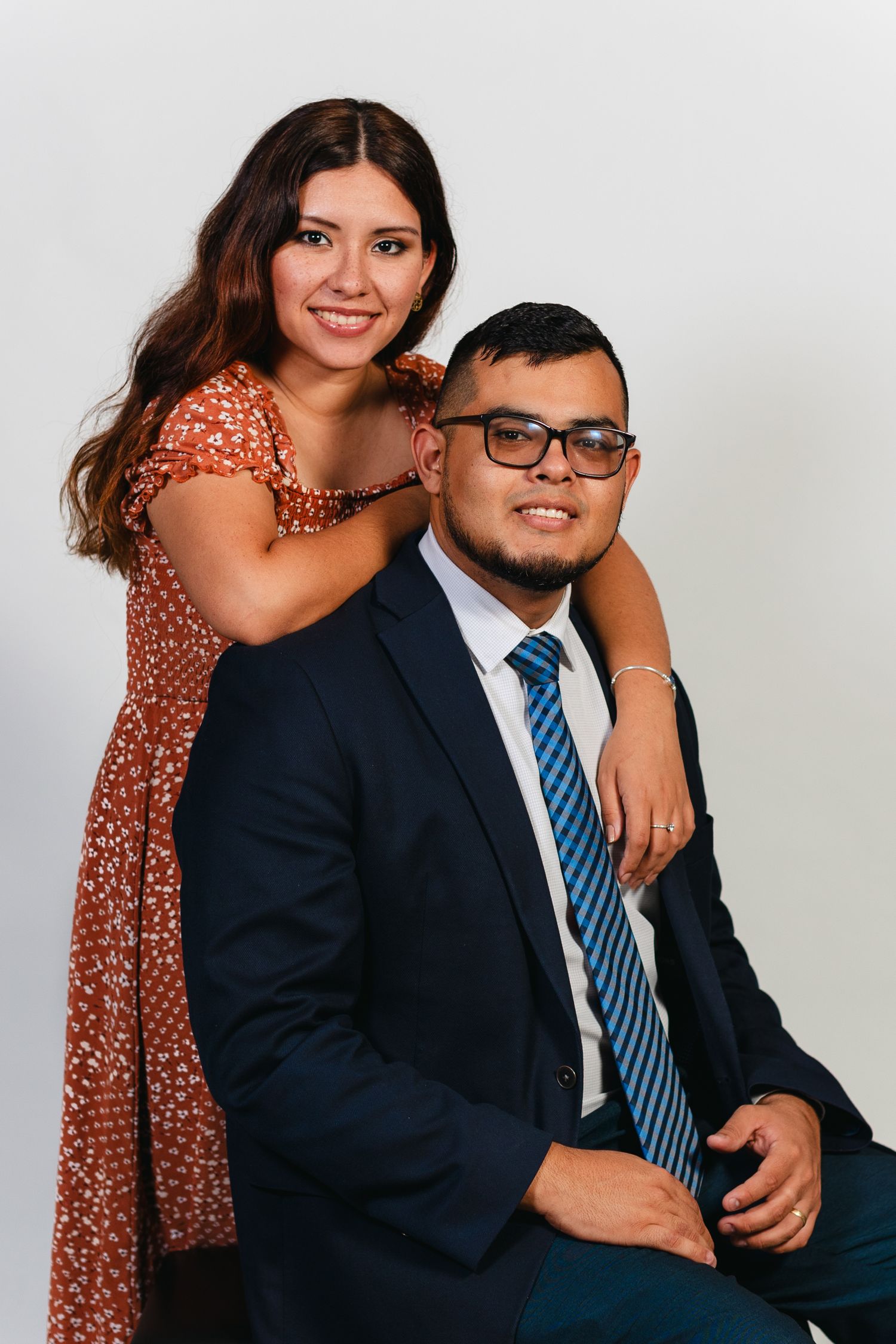 Happy couple poses for portrait with woman standing behind seated partner.