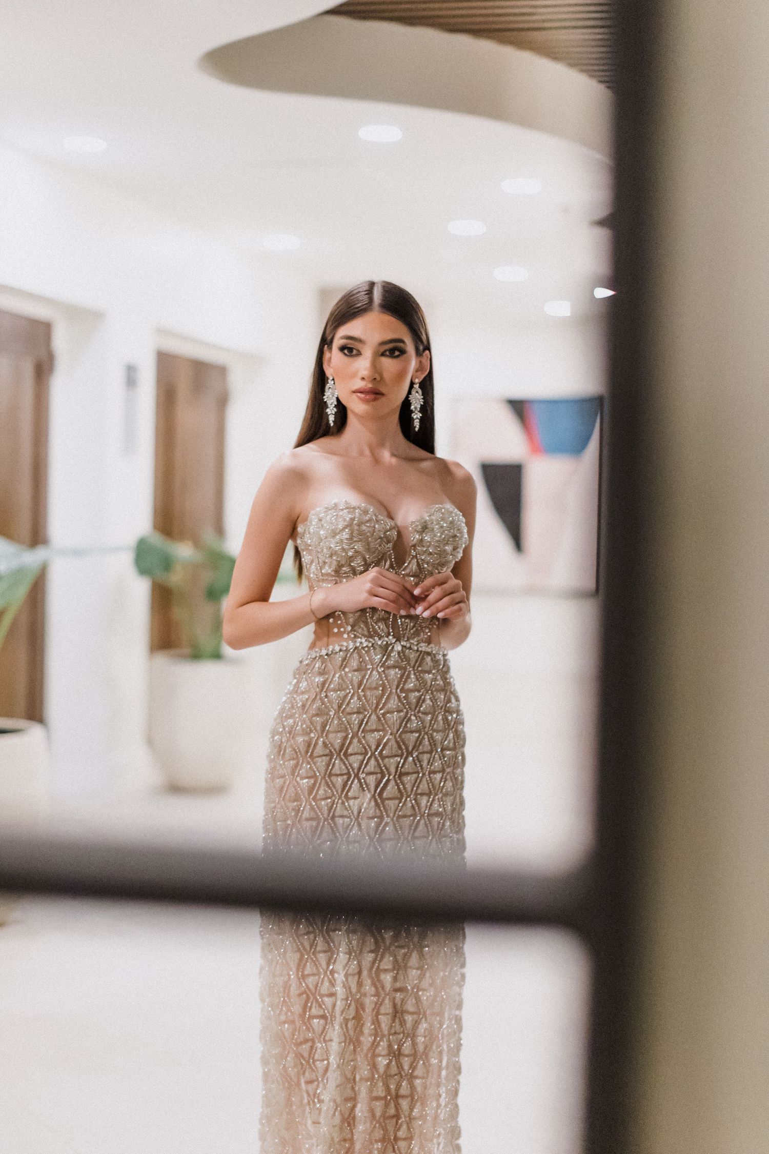 A glamorous evening gown with intricate beading and embellishments is showcased in multiple angles through window panes.