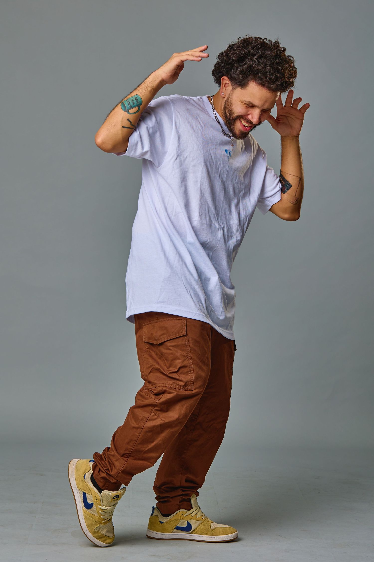 Dynamic pose of person in casual attire dancing against grey background.