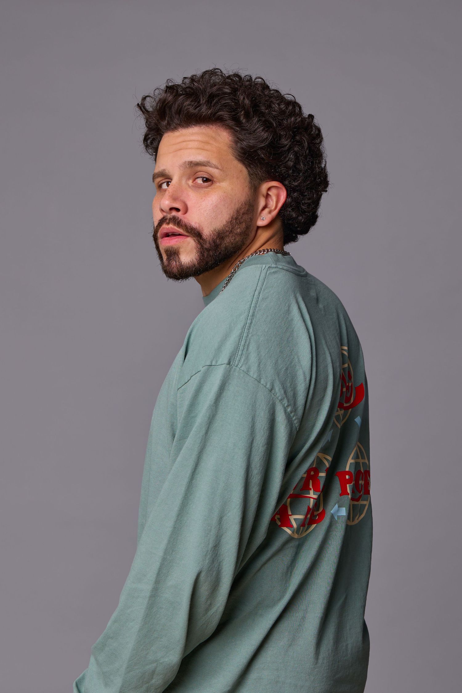 Side profile portrait of person in sage green sweatshirt against grey background.