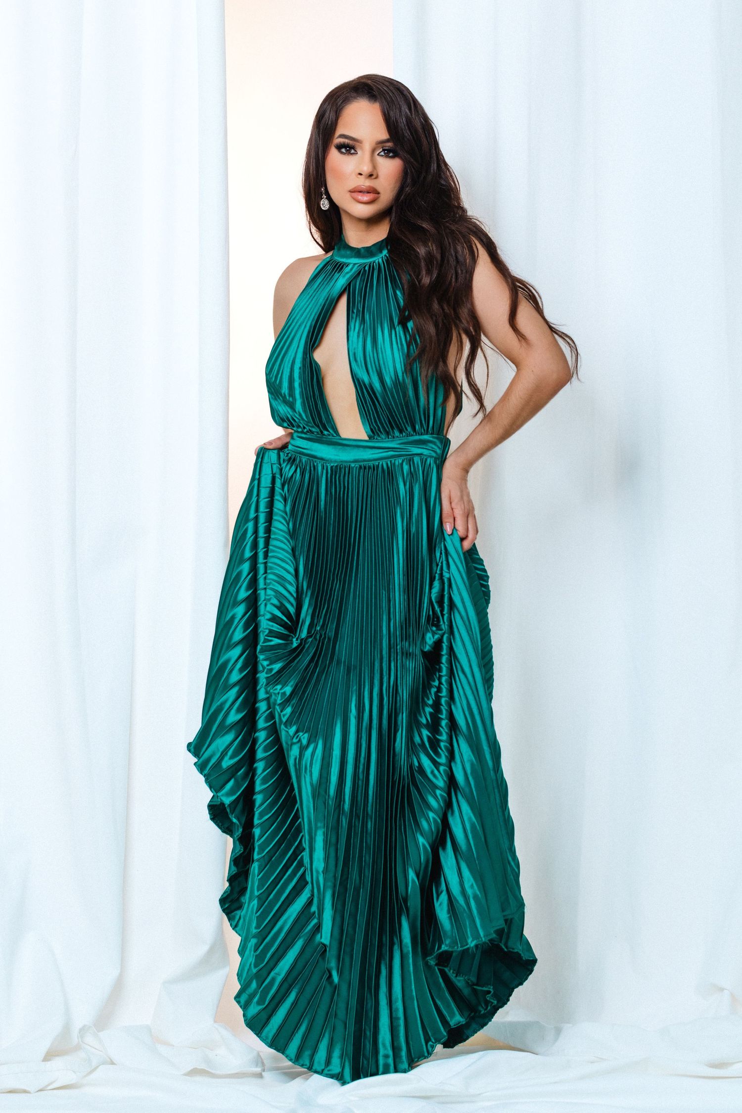 Glamorous pleated emerald green satin evening gown with halter neckline and dramatic flowing skirt.
