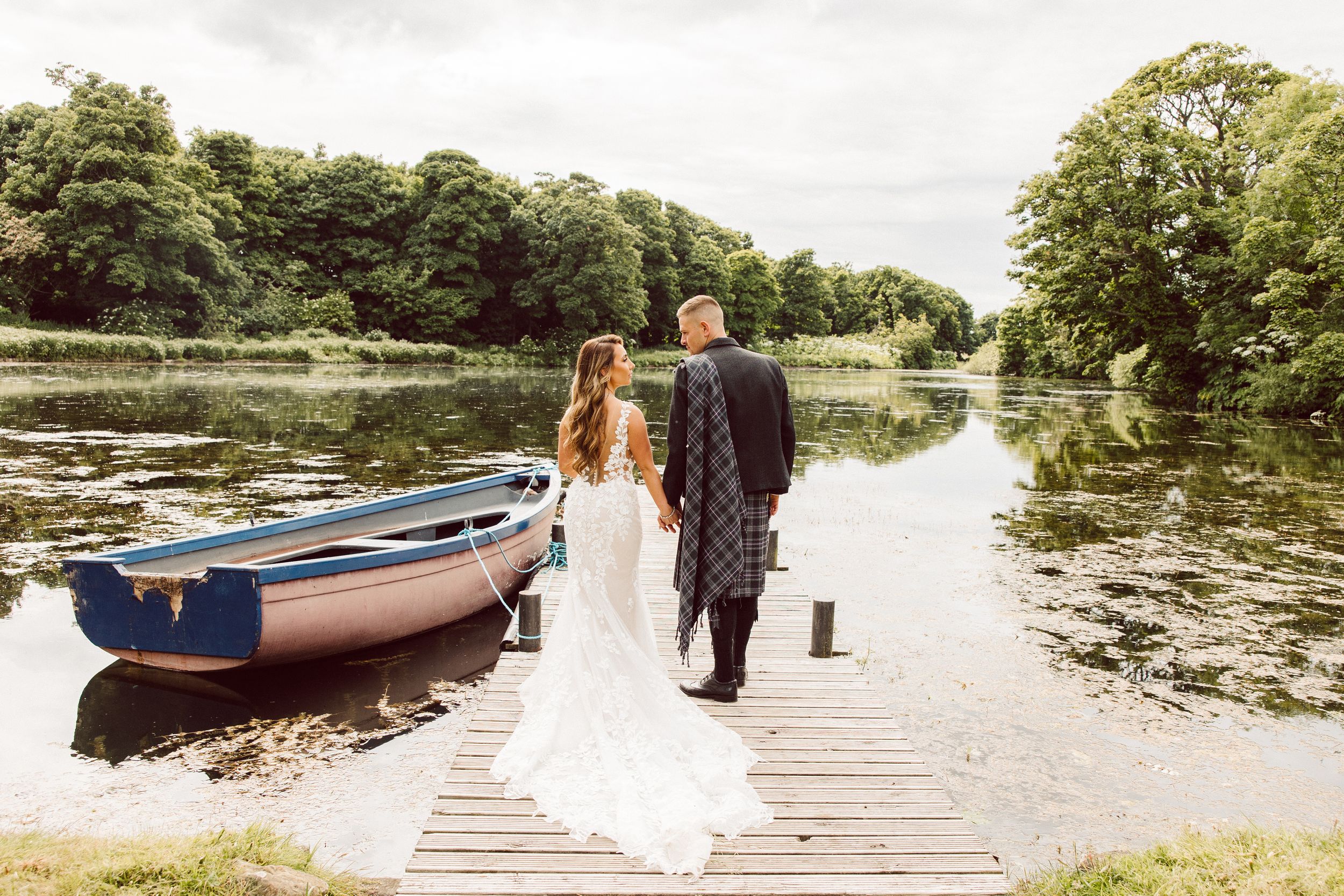 A series of wooden docks extend over calm lake waters surrounded by lush green trees and vegetation.