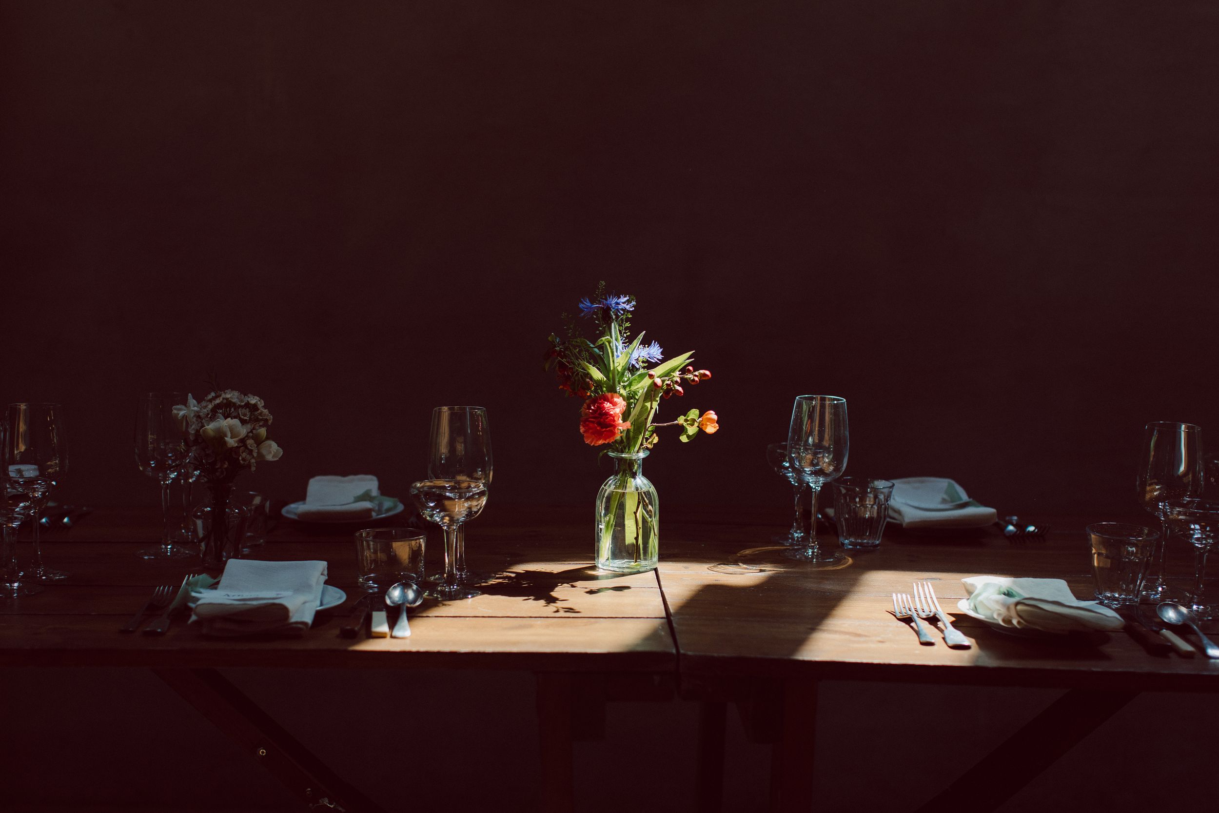 A series of dark restaurant tables illuminated by small table lamps creating an intimate dining atmosphere.