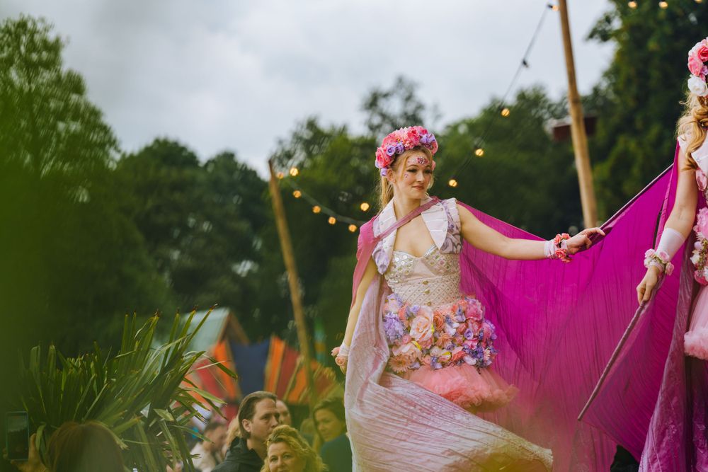 Performer in floral dress and crown during outdoor festival performance.
