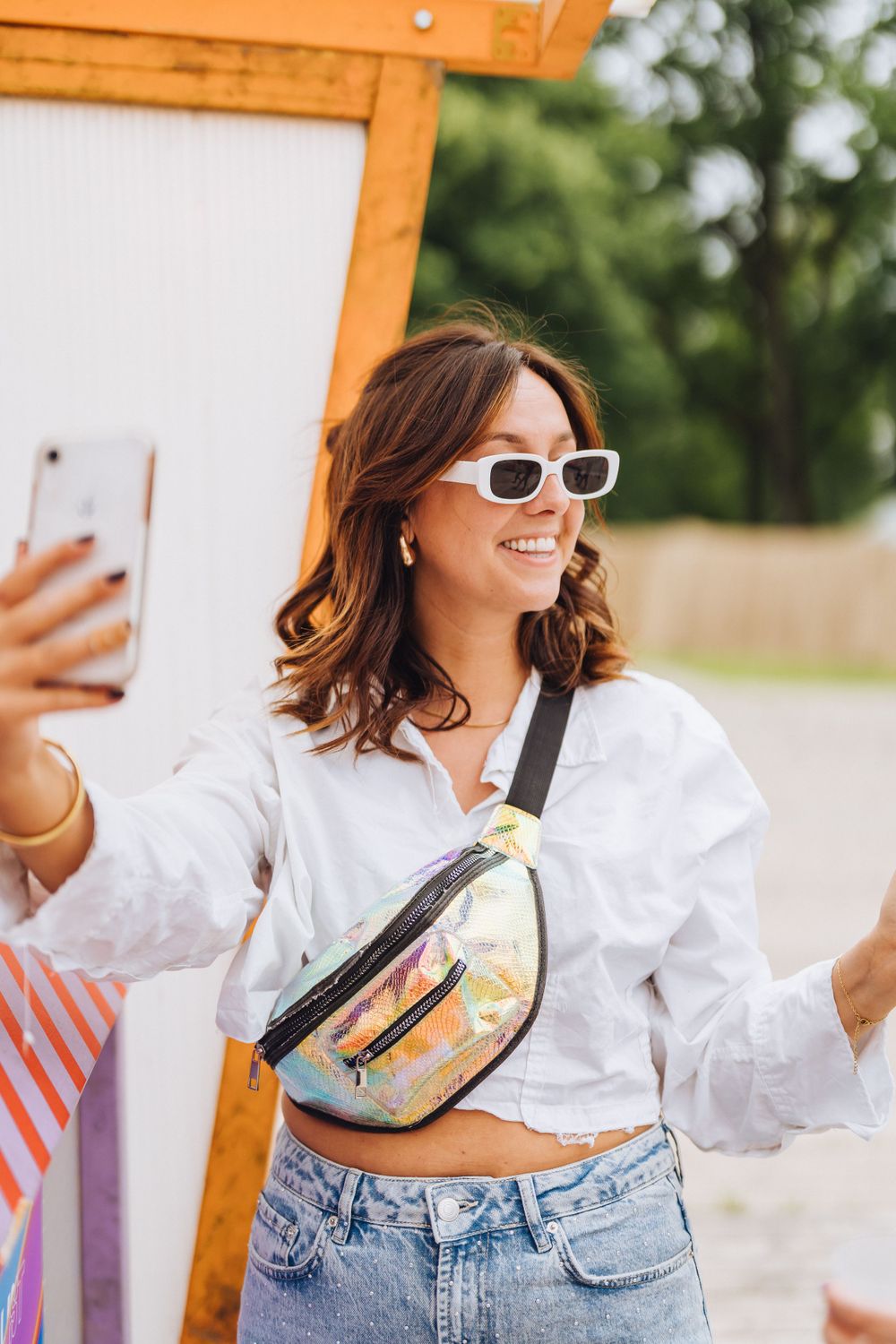 Summer festival style with white crop top, denim and holographic fanny pack.