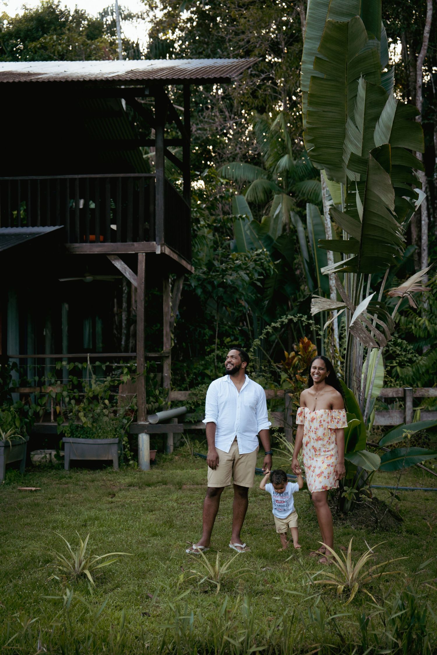 Couple devant une maison en bois dans un jardin en Guyane