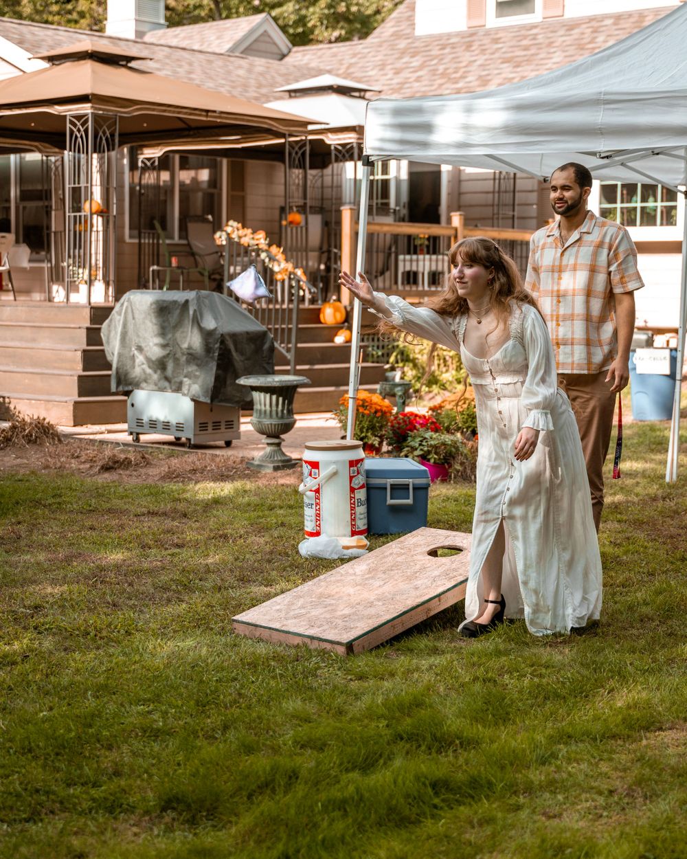 People enjoying a backyard party with tents and lawn games during golden hour.