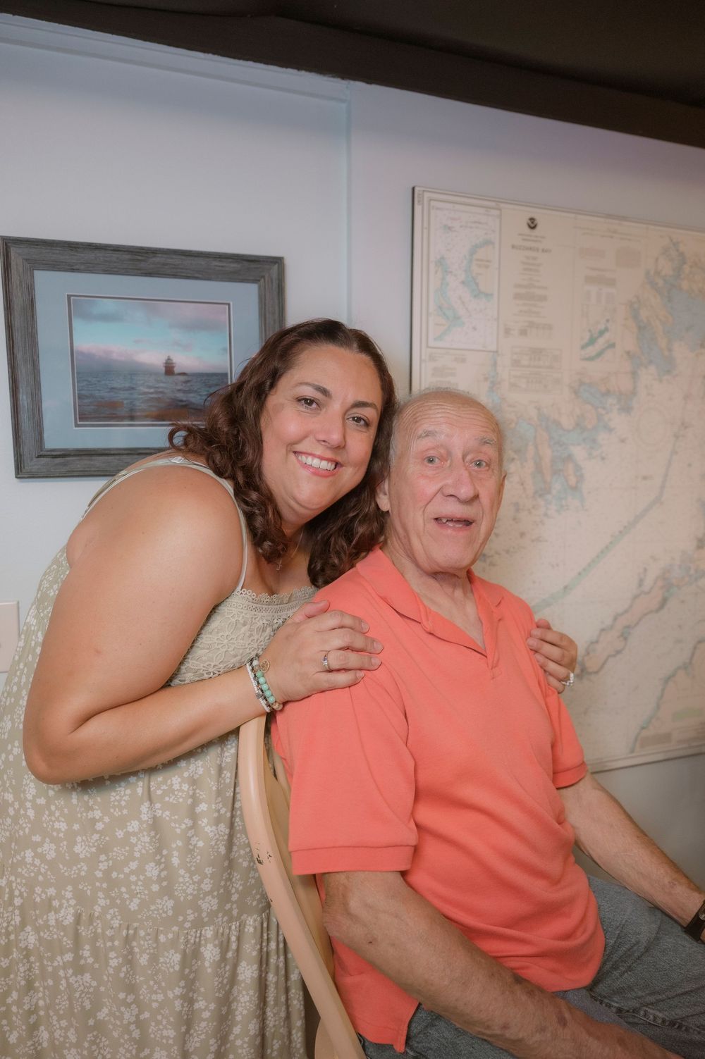Two people sit together on a couch in a room with maps and artwork on the walls.