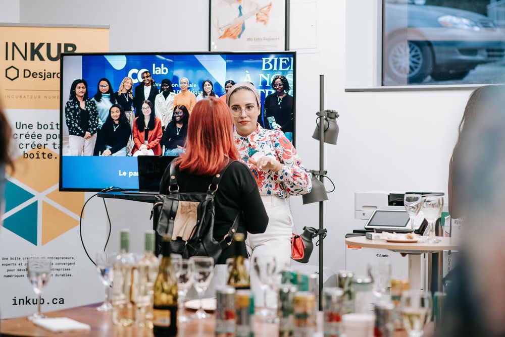Professional networking event with TV display and refreshment table visible.