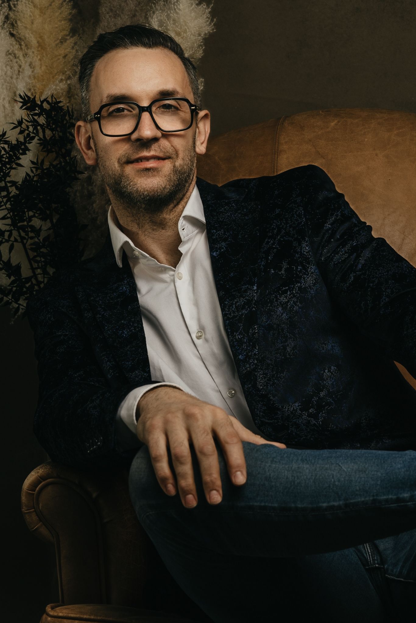 Professional portrait in moody lighting against a dark textured background.