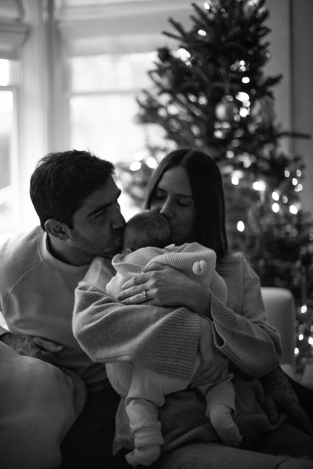 A black and white family moment by the Christmas tree.