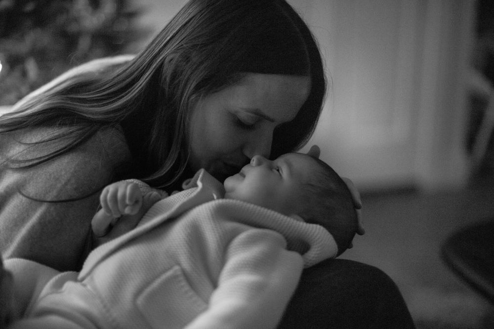 An intimate black and white photograph of a tender moment with a baby.