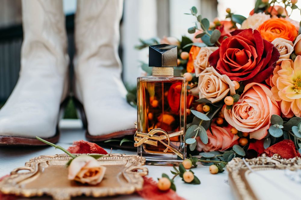 Romantic wedding details with peach and red roses alongside stationery and decor elements on white surface.